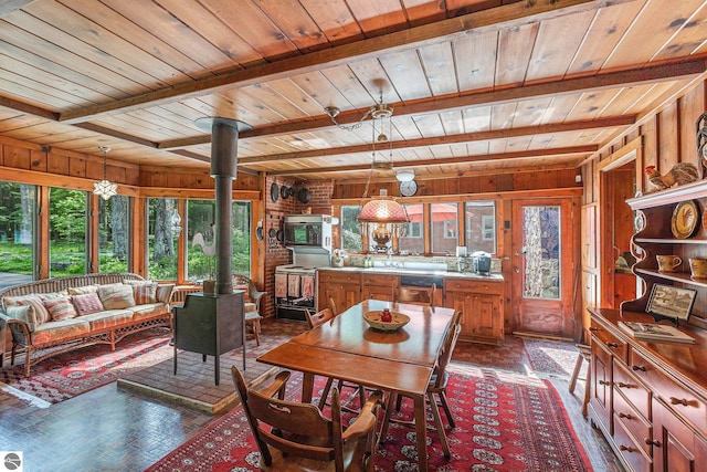 7822 W Welch Rd, Empire, MI 49630 - dining room featuring a wood ceiling with exposed beams, wooden walls, and a wood stove