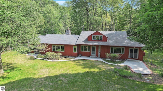 7822 W Welch Rd, Empire, MI 49630 - view of front of property with a front yard, a chimney, a view of trees, a porch, and a shingled roof