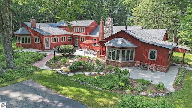 7822 W Welch Rd, Empire, MI 49630 - rear view of property with a chimney, a patio, and roof with shingles