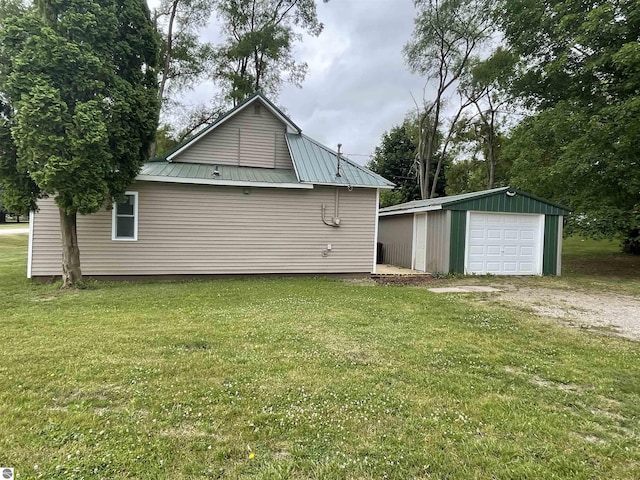 702 N Grafton Ave, Alma, MI 48801 - view of side of home featuring a garage, driveway, an outbuilding, a metal roof, and a lawn