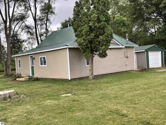 702 N Grafton Ave, Alma, MI 48801 - view of side of home featuring a detached garage, a metal roof, and a lawn