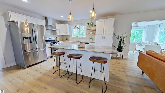 84 9 Mile Rd NW, Comstock Park, MI 49321 - kitchen with appliances with stainless steel finishes, wall chimney range hood, light wood finished floors, a breakfast bar, and recessed lighting