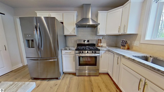84 9 Mile Rd NW, Comstock Park, MI 49321 - kitchen with wall chimney exhaust hood, stainless steel appliances, white cabinetry, light wood-style floors, and backsplash