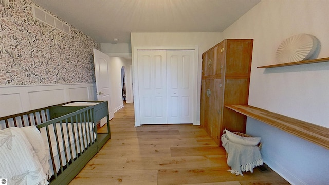 84 9 Mile Rd NW, Comstock Park, MI 49321 - unfurnished bedroom featuring wainscoting, a closet, light wood finished floors, and arched walkways