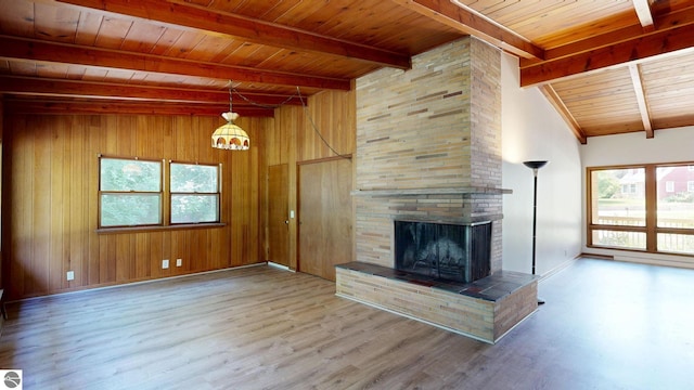 1519 Ridge Rdg, Mount Pleasant, MI 48858 - unfurnished living room with a wood ceiling with exposed beams, a fireplace, healthy amount of natural light, wood finished floors, and wooden walls