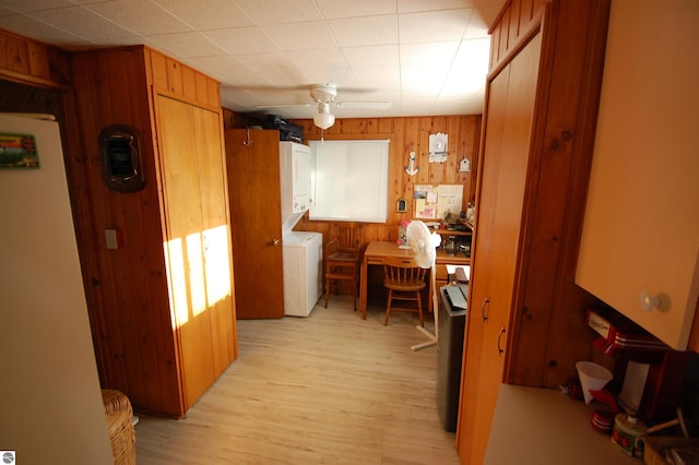 4038 Ogemaw Shores Dr, West Branch, MI 48661 - kitchen with wooden walls, stacked washing machine and dryer, brown cabinetry, and light wood-type flooring