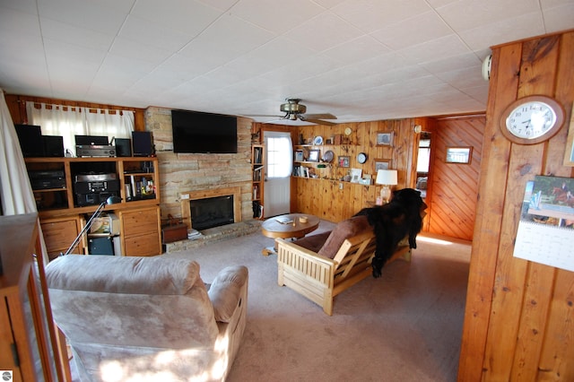 4038 Ogemaw Shores Dr, West Branch, MI 48661 - living area featuring carpet, a stone fireplace, a ceiling fan, and wood walls