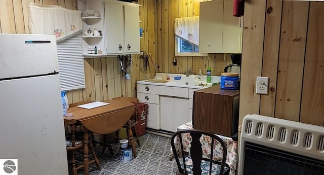 1947 NE Anita Rd, Kalkaska, MI 49646 - kitchen featuring freestanding refrigerator, heating unit, open shelves, wood walls, and light countertops