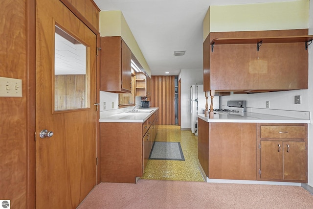 7786 N Shore Ct, Grawn, MI 49637 - kitchen featuring brown cabinets, light countertops, range, and freestanding refrigerator