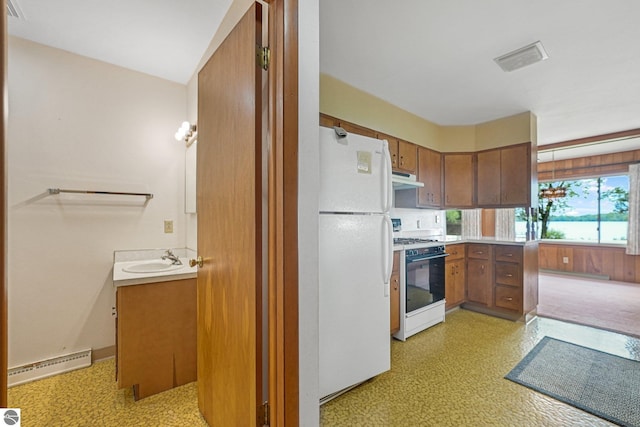 7786 N Shore Ct, Grawn, MI 49637 - kitchen featuring white appliances, a baseboard heating unit, under cabinet range hood, light countertops, and brown cabinetry