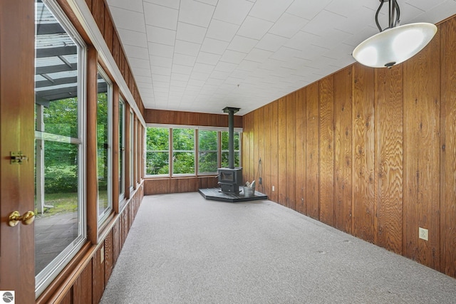 7786 N Shore Ct, Grawn, MI 49637 - unfurnished sunroom with a wood stove, carpet, and wood walls