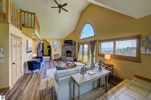10702 E Hill Top Rd, Suttons Bay, MI 49682 - living room with a ceiling fan, high vaulted ceiling, a fireplace, arched walkways, and wood finished floors