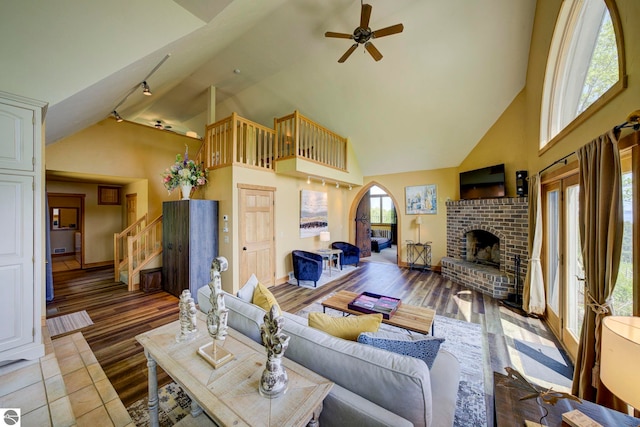 10702 E Hill Top Rd, Suttons Bay, MI 49682 - living area with ceiling fan, high vaulted ceiling, a fireplace, stairs, and wood finished floors