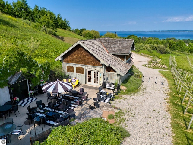 10702 E Hill Top Rd, Suttons Bay, MI 49682 - rear view of property with french doors, gravel driveway, a water view, and a patio area