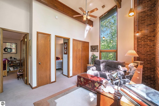 6740 Pheasant Run, Gaylord, MI 49735 - carpeted living room featuring high vaulted ceiling, beam ceiling, plenty of natural light, ceiling fan, and brick wall