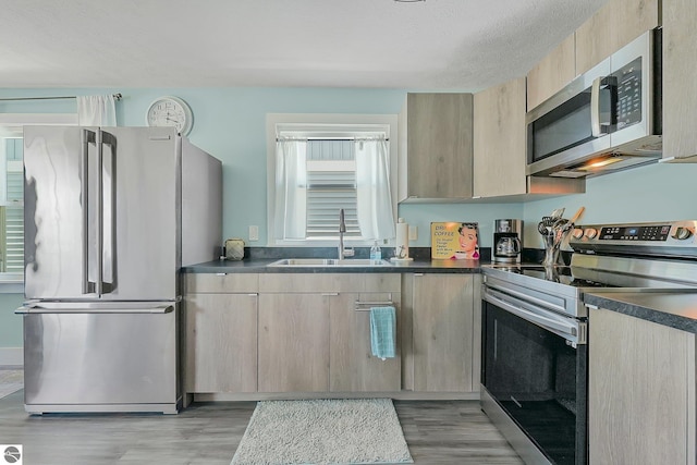 1029 E Front St, Traverse City, MI 49686 - kitchen featuring stainless steel appliances, light wood-style floors, light brown cabinets, dark countertops, and a textured ceiling