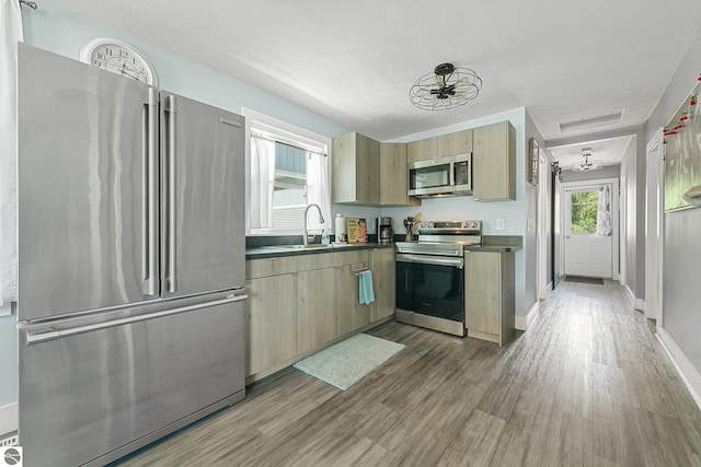 1029 E Front St, Traverse City, MI 49686 - kitchen with appliances with stainless steel finishes, dark countertops, wood finished floors, and light brown cabinets