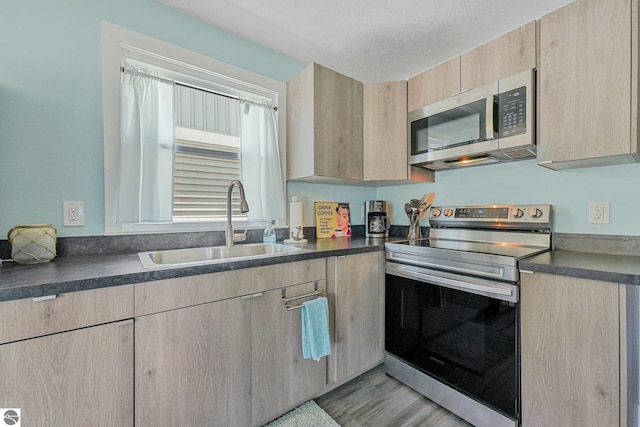 1029 E Front St, Traverse City, MI 49686 - kitchen featuring appliances with stainless steel finishes, light brown cabinets, dark countertops, light wood-style floors, and a textured ceiling
