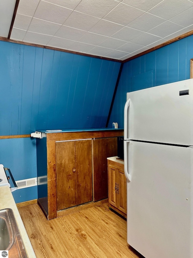 3775 W Cedar Lake Rd, Greenbush, MI 48738 - kitchen with freestanding refrigerator, light wood-style flooring, brown cabinetry, and light countertops