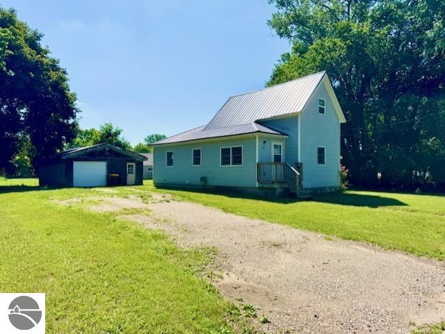 219 Grafton Ave, Alma, MI 48801 - view of home's exterior featuring dirt driveway, a garage, a lawn, an outbuilding, and a metal roof