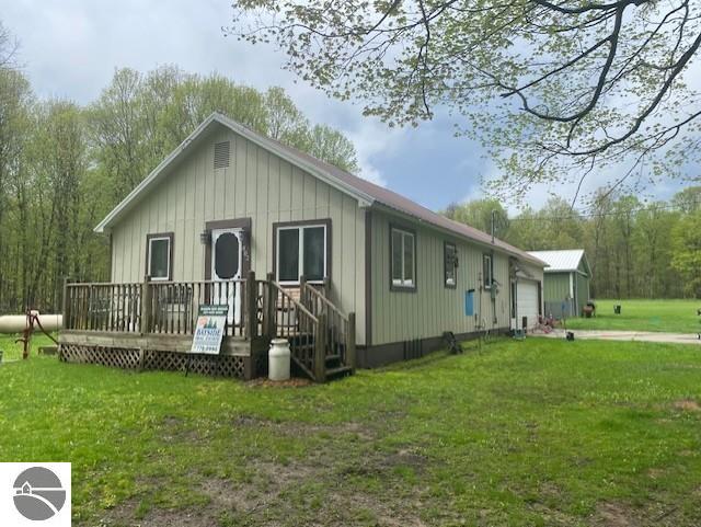 802 W 4th Rd, Buckley, MI 49620 - view of front of property with a front yard, board and batten siding, a wooden deck, and a garage