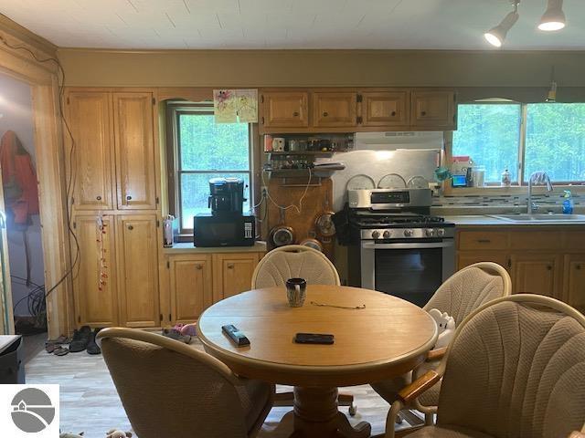 802 W 4th Rd, Buckley, MI 49620 - kitchen with stainless steel range with gas stovetop, black microwave, under cabinet range hood, and plenty of natural light