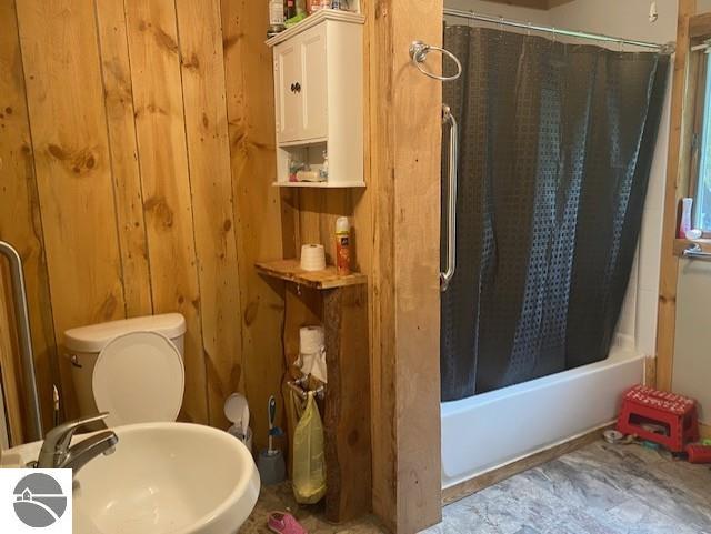 802 W 4th Rd, Buckley, MI 49620 - bathroom featuring shower / bath combination with curtain and wooden walls