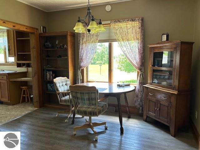 2393 Oates Rd, Tawas City, MI 48763 - dining room featuring a chandelier, plenty of natural light, wood finished floors, and ornamental molding