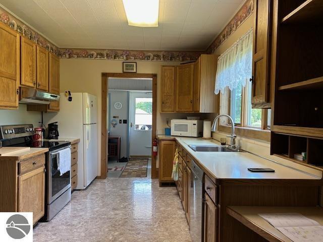 2393 Oates Rd, Tawas City, MI 48763 - kitchen with stainless steel appliances, under cabinet range hood, light countertops, light floors, and brown cabinetry
