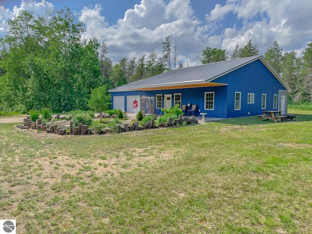 5670 N Harrison Ave, Harrison, MI 48625 - rear view of property with a yard, a vegetable garden, a metal roof, and a garage