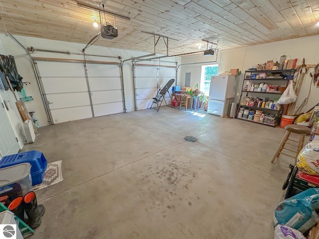 5670 N Harrison Ave, Harrison, MI 48625 - garage featuring freestanding refrigerator, electric panel, and a garage door opener