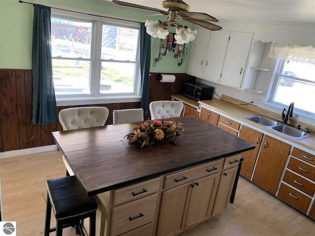 13333 S Coleman Rd, Empire, MI 49630 - kitchen with a ceiling fan, butcher block counters, wooden walls, light wood-style floors, and white cabinets