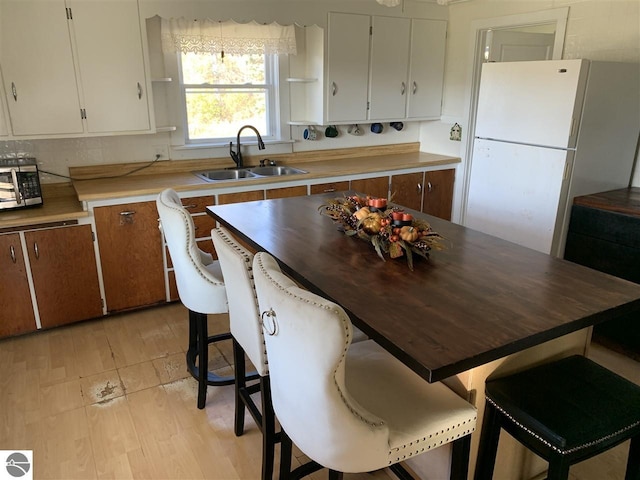 13333 S Coleman Rd, Empire, MI 49630 - kitchen featuring open shelves, freestanding refrigerator, stainless steel microwave, light countertops, and light wood finished floors