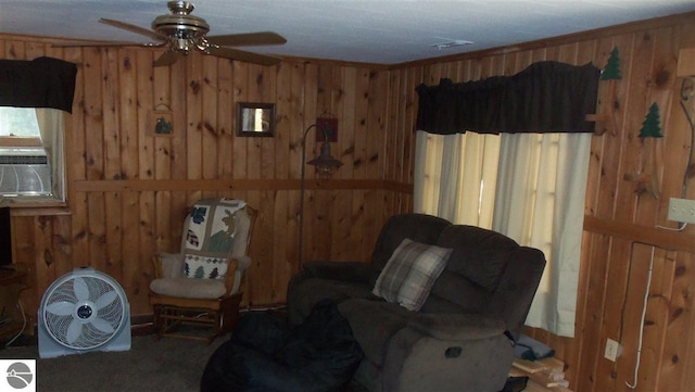 living area featuring ceiling fan and wooden walls