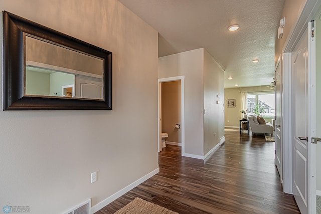 corridor featuring a textured ceiling and dark hardwood / wood-style flooring