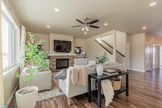 living room with wood-type flooring, ceiling fan, and a fireplace