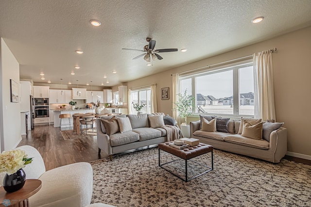 living room with a textured ceiling, ceiling fan, and hardwood / wood-style floors