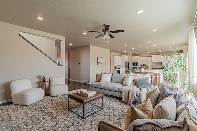 living room featuring ceiling fan, a textured ceiling, and light hardwood / wood-style flooring