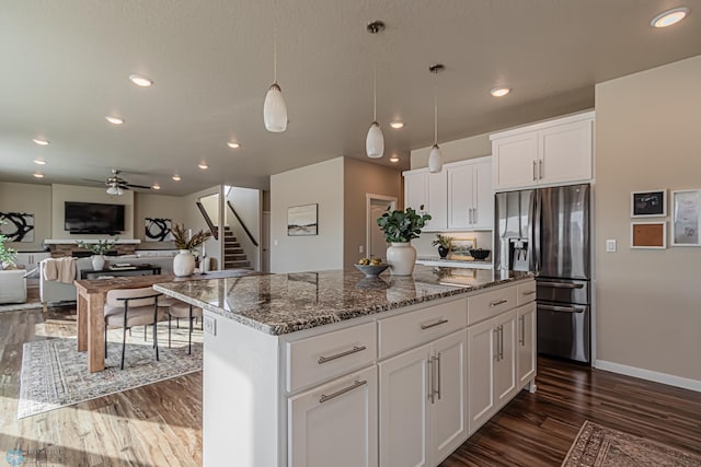 kitchen featuring a center island, stainless steel fridge, white cabinets, dark hardwood / wood-style floors, and pendant lighting