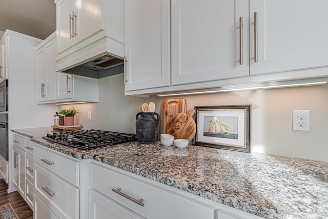 kitchen featuring white cabinetry, hardwood / wood-style flooring, light stone counters, black gas stovetop, and oven