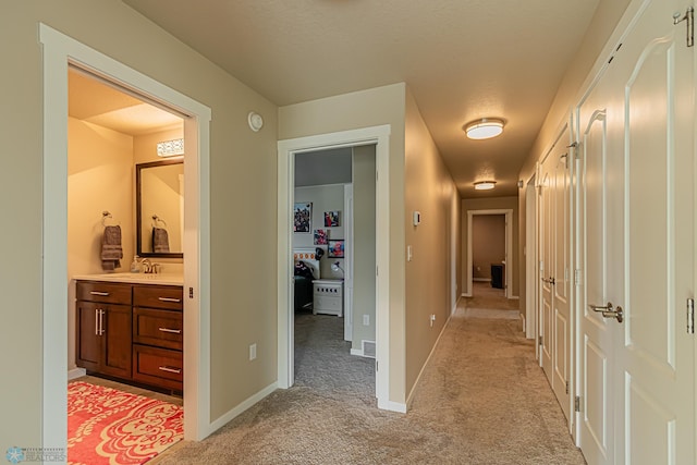 hallway featuring light colored carpet and sink