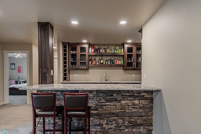 bar with carpet flooring and light stone counters