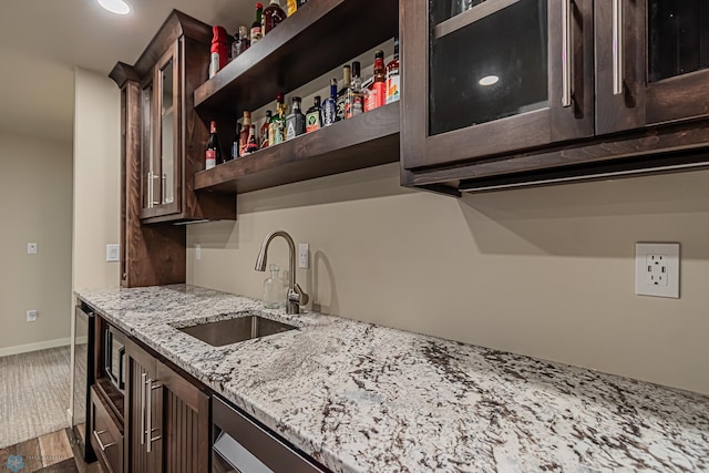 kitchen featuring dark brown cabinetry, hardwood / wood-style floors, sink, and light stone counters