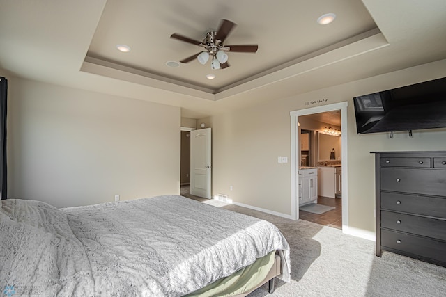 carpeted bedroom featuring ensuite bathroom, ceiling fan, and a raised ceiling