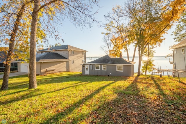 back of property with a water view and a yard