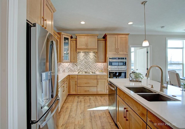 kitchen featuring hanging light fixtures, stainless steel appliances, light hardwood / wood-style floors, tasteful backsplash, and sink