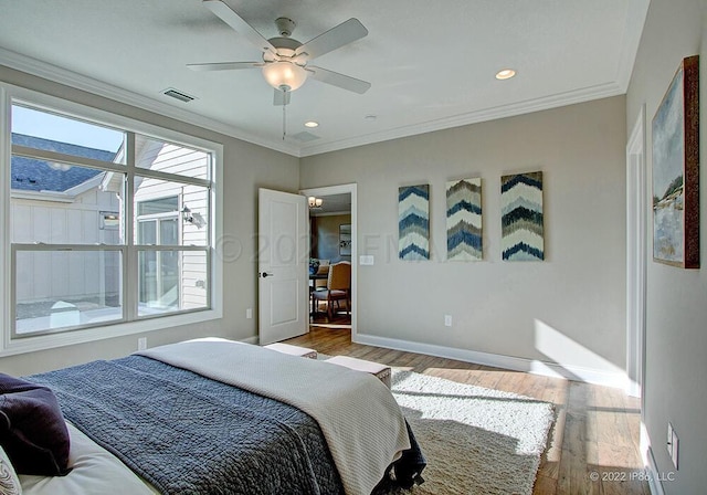 bedroom with hardwood / wood-style floors, ceiling fan, and ornamental molding