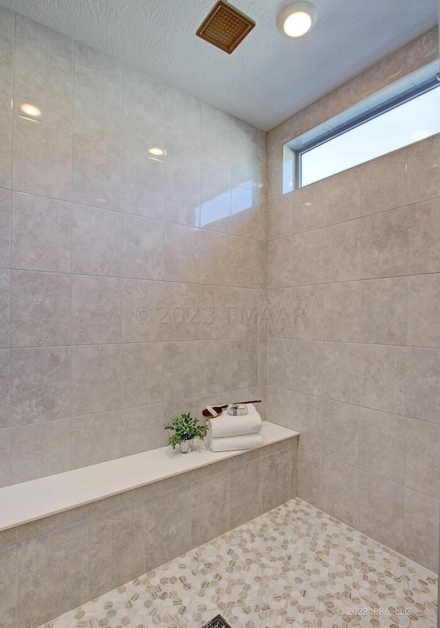 bathroom featuring a textured ceiling and a tile shower