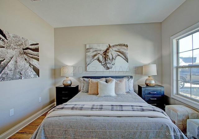 bedroom with hardwood / wood-style floors and multiple windows