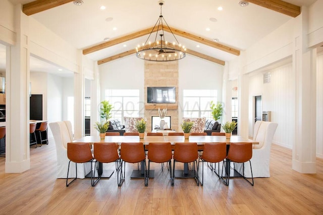 dining area with a notable chandelier, beam ceiling, and light wood-type flooring